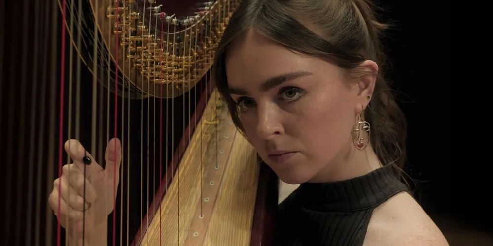 Yvonne looks out from behind the strings of her harp