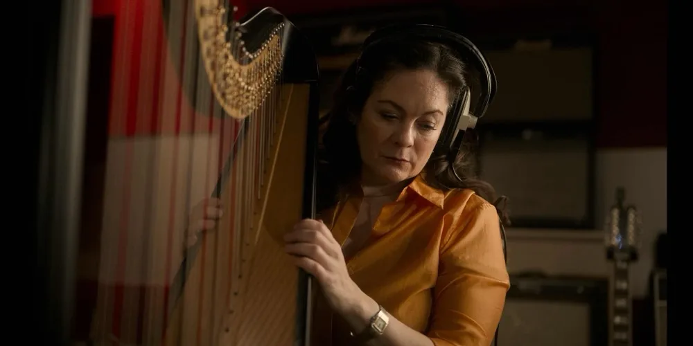 Maria records a harp part in the studio wearing headphones